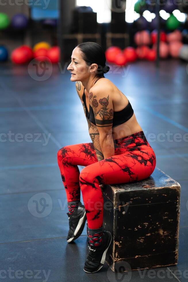 Mature athlete resting sitting on a box in a gym photo