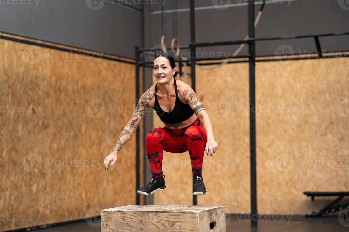 Mature woman jumping into box in a gym photo