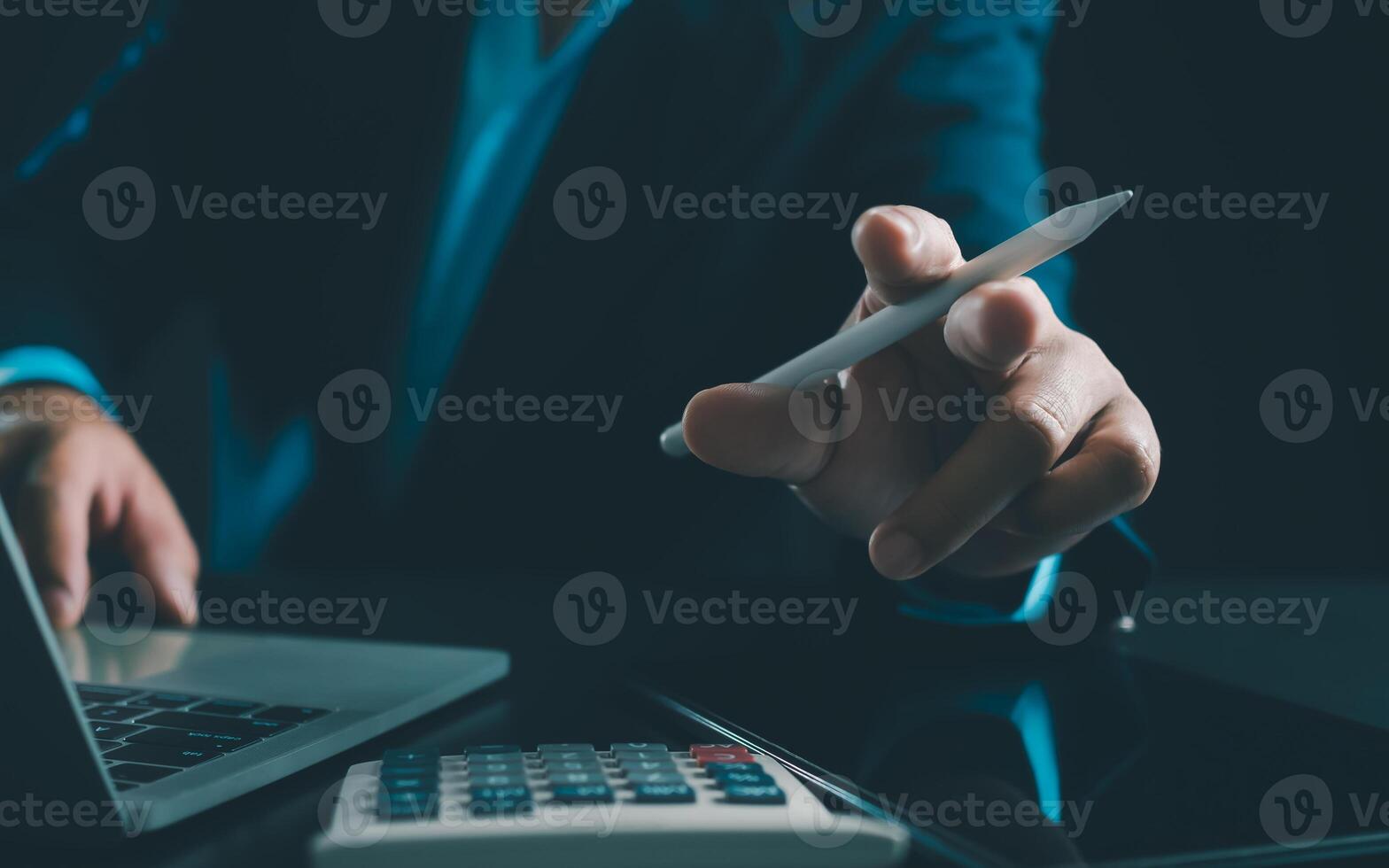 Businessman in black suit working on laptop computer and tablet and calculator, Hand Hands touch on tablet at office with dark background, Online working, Close up, Copy space. photo