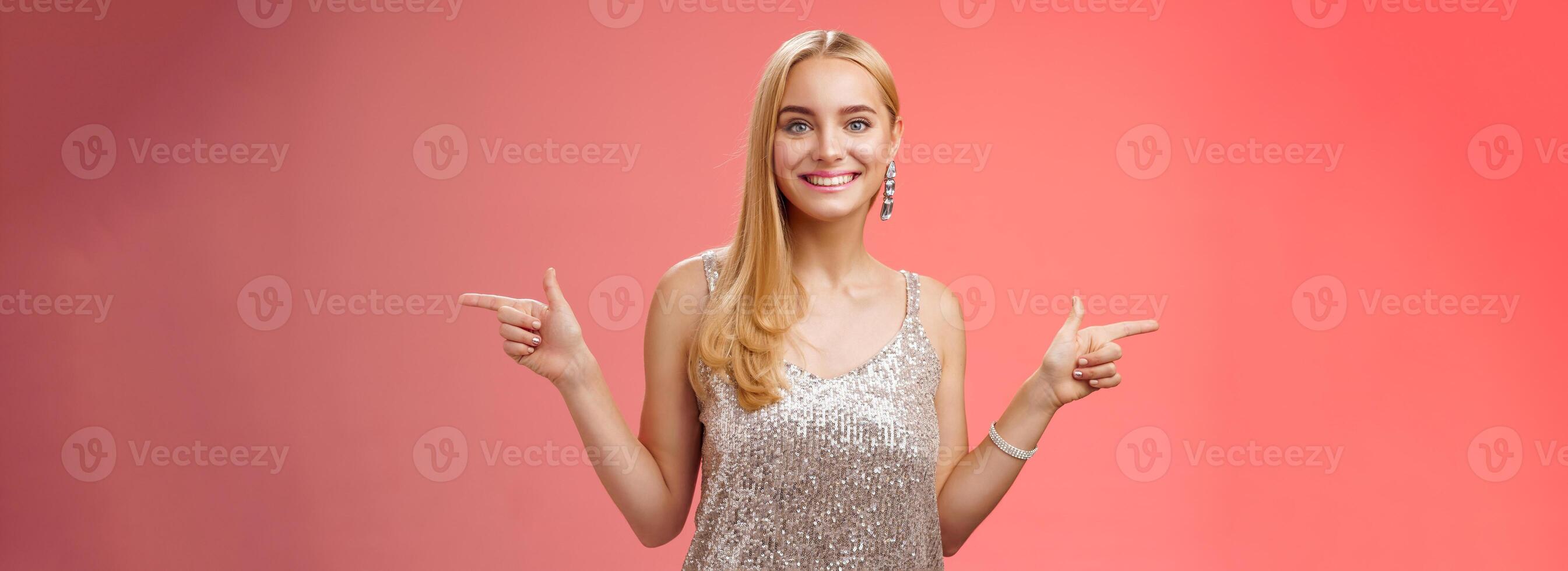 Waist-up shot energized cheerful blond european girl in silver glittering dress pointing sideways left right smiling amused showing lots variants variety opportunities make choice which better photo