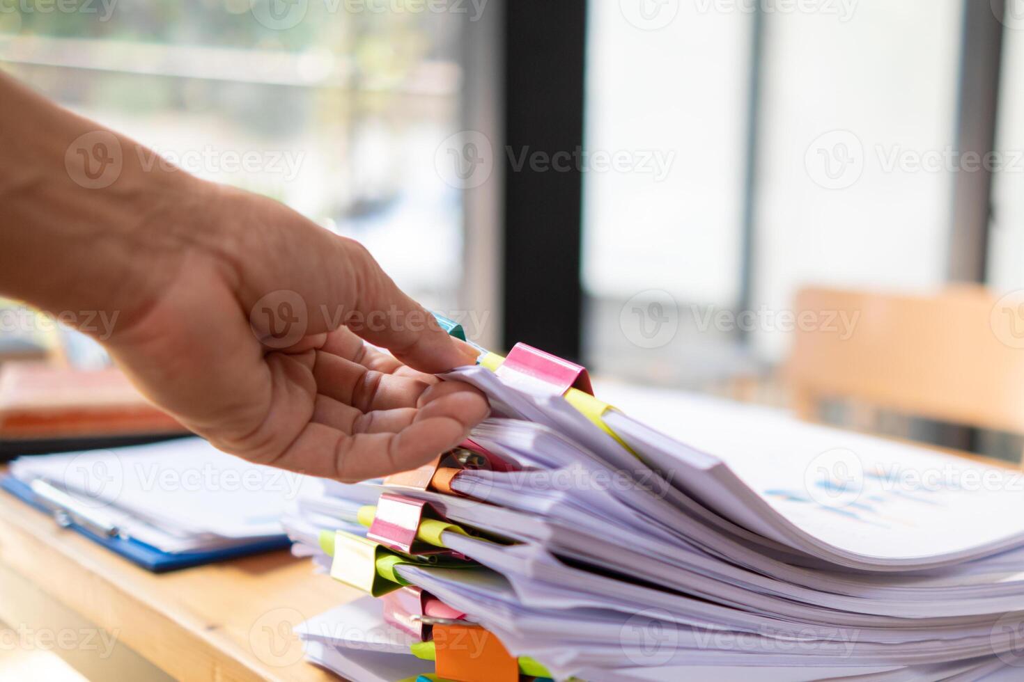 A young secretary receives a pile of documents to find important information for the company manager to use in a meeting. The concept of finding important documents from piles of overlapping documents photo