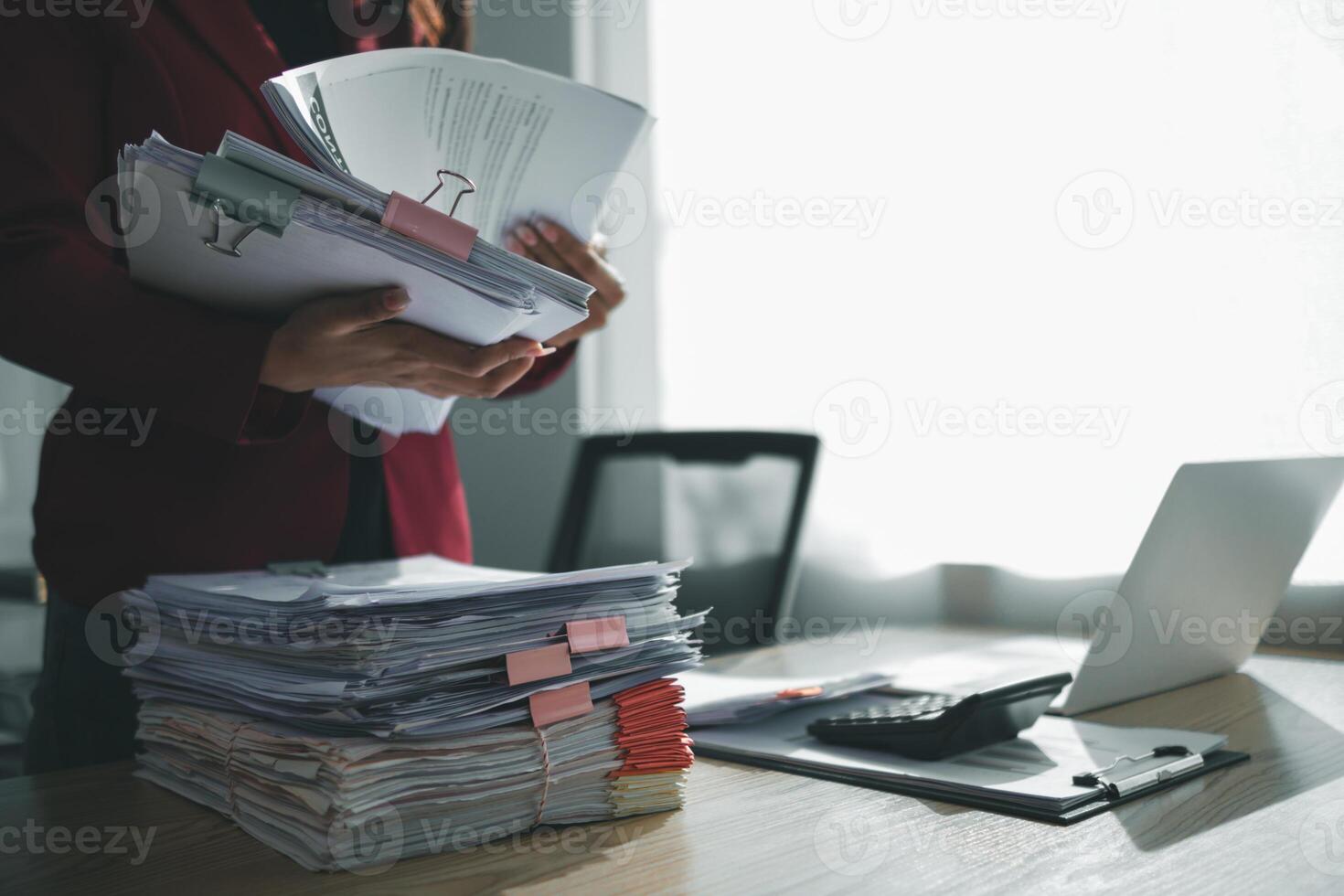 The pile of documents on the secretary's desk was prepared for the executives who would be attending the meeting. Several documents were stacked on the secretary's desk ready for the attendees. photo