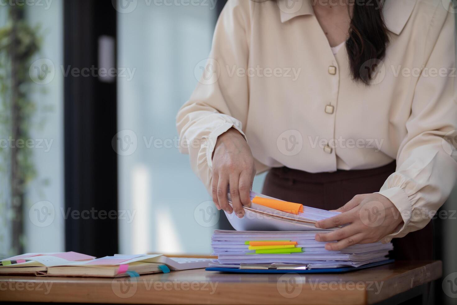 secretary is searching through pile of important documents on office table deliver them to manager for presentation in time at meeting. Concept of difficulty finding information from piles of document photo