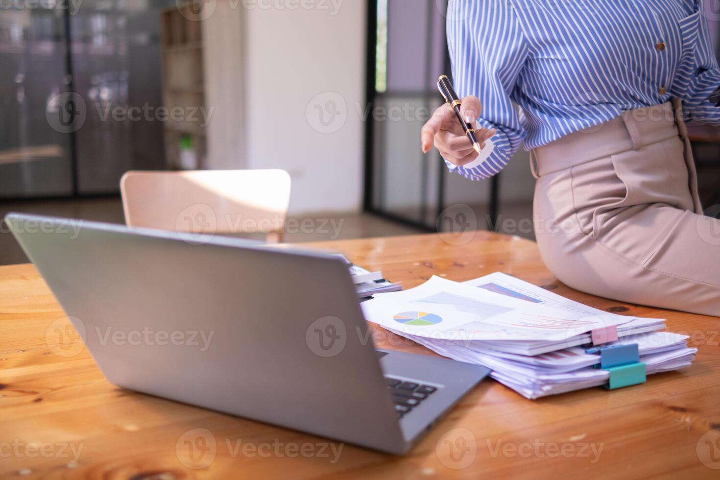 A young secretary is searching through the pile of documents on her desk to prepare for an executive meeting. The secretary looked exhausted from searching through the pile of documents on her desk. photo