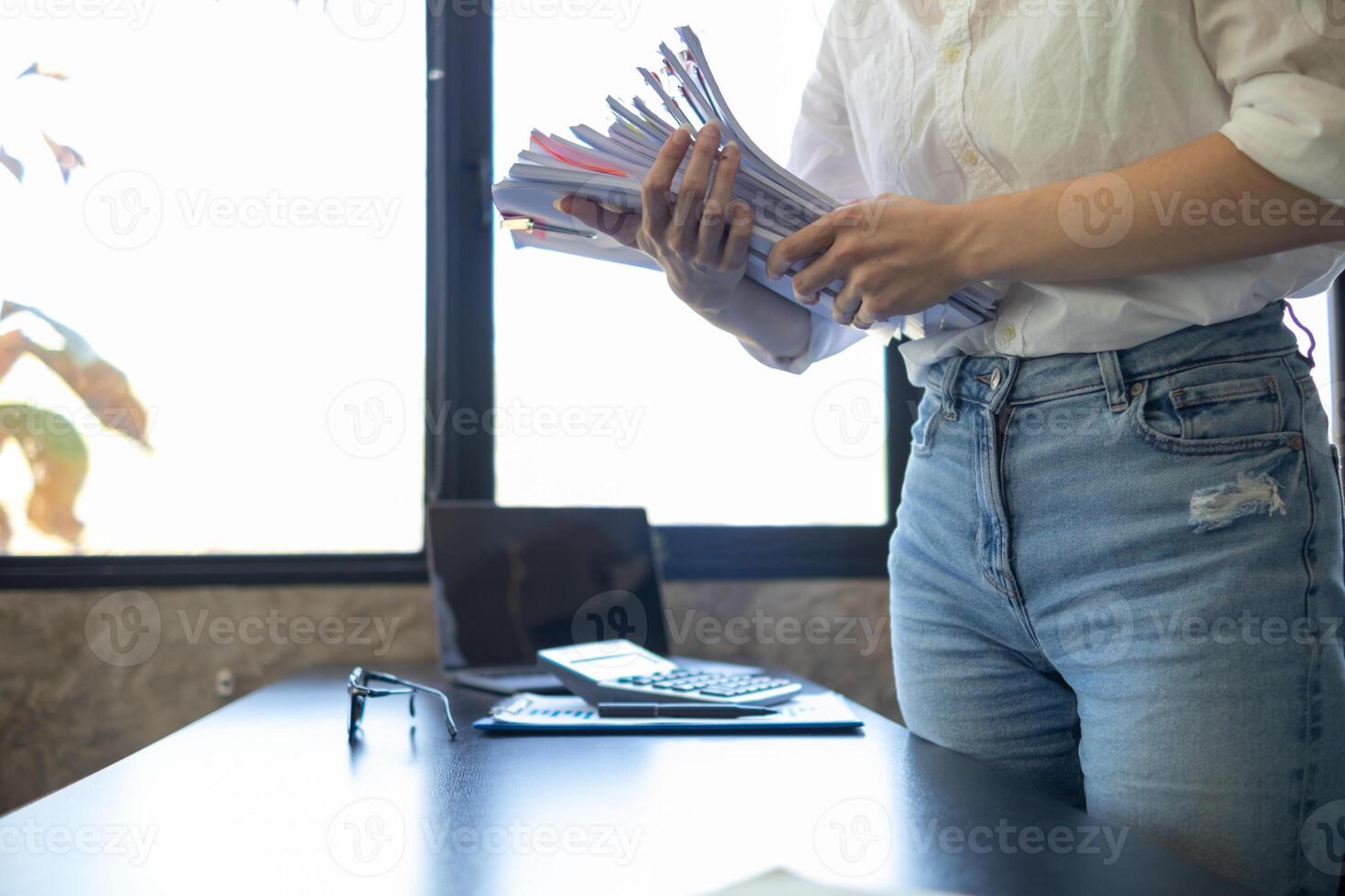 A young secretary receives a pile of documents to find important information for the company manager to use in a meeting. The concept of finding important documents from piles of overlapping documents photo