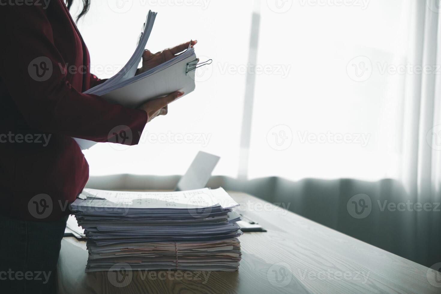 A young secretary receives a pile of documents to find important information for the company manager to use in a meeting. The concept of finding important documents from piles of overlapping documents photo
