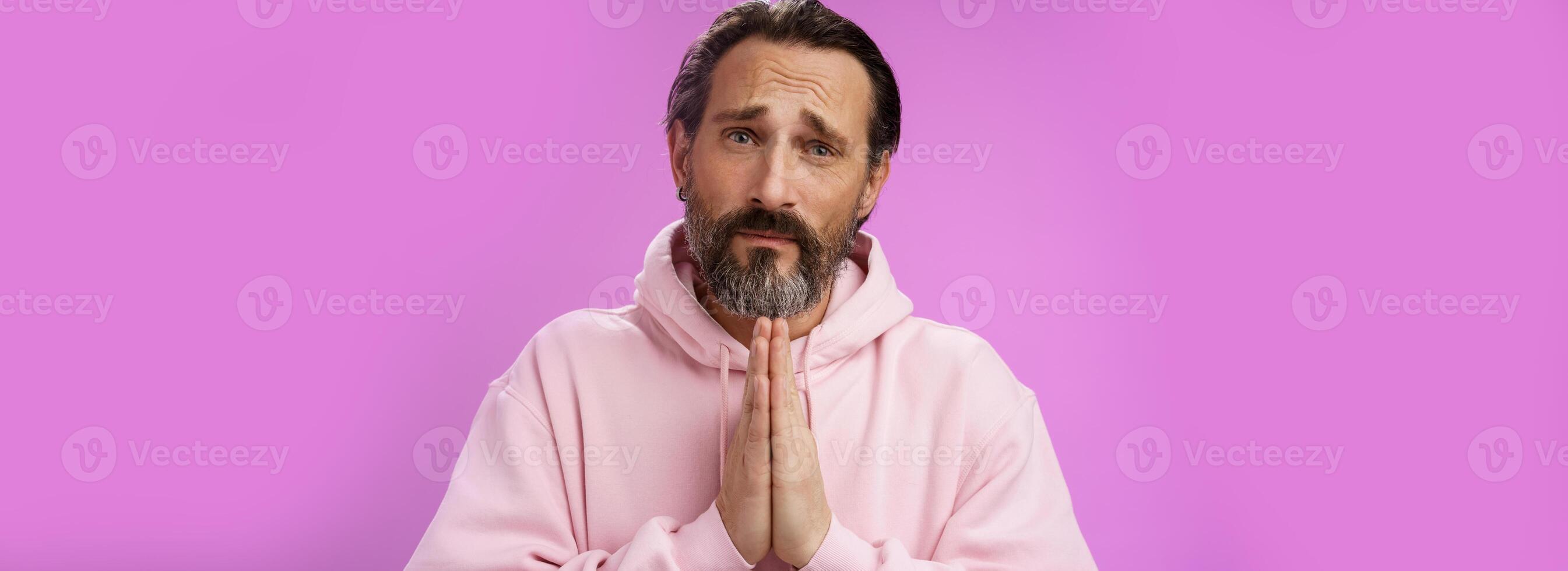 Upset handsome bearded mature man need help asking forgiveness supplicating press palms together praying frowning sorrow begging favour lend money, standing purple background miserable photo