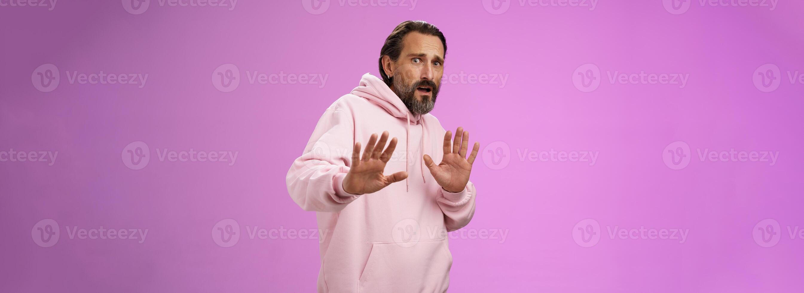 Wow slow down not touch me. Insecure silly unconfident adult weak scared guy raising palms protection frowning widen eyes look nervous disturbed frightened robber, standing purple backgroud afraid photo