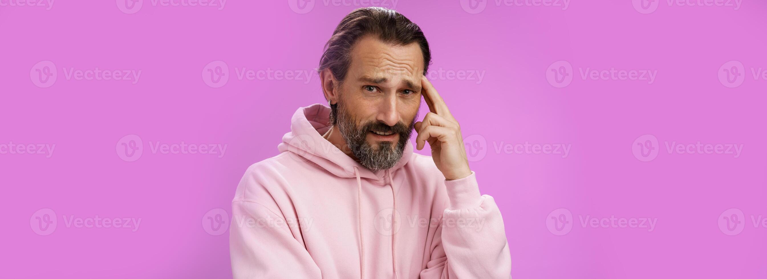 Man hearing ridiculous nonsense talks bothered pissed frowning cringing from dislike disagree touch temple not sure person use brain, standing purple background hesitant doubtful displeased photo