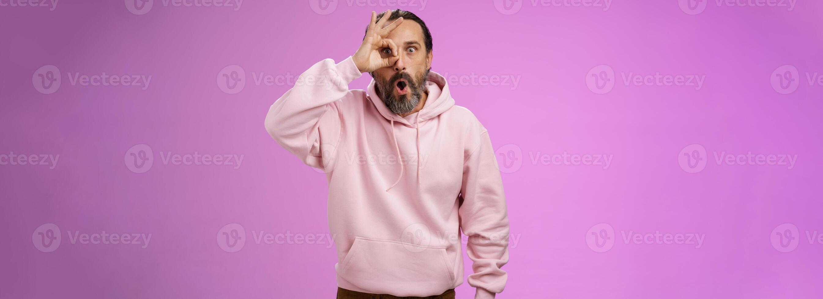 Impressed speechless handsome stylish old man bearded grey hair say wow drop jaw see incredible discount show okay ok excellent gesture eye look through amazed, standing pleased purple background photo