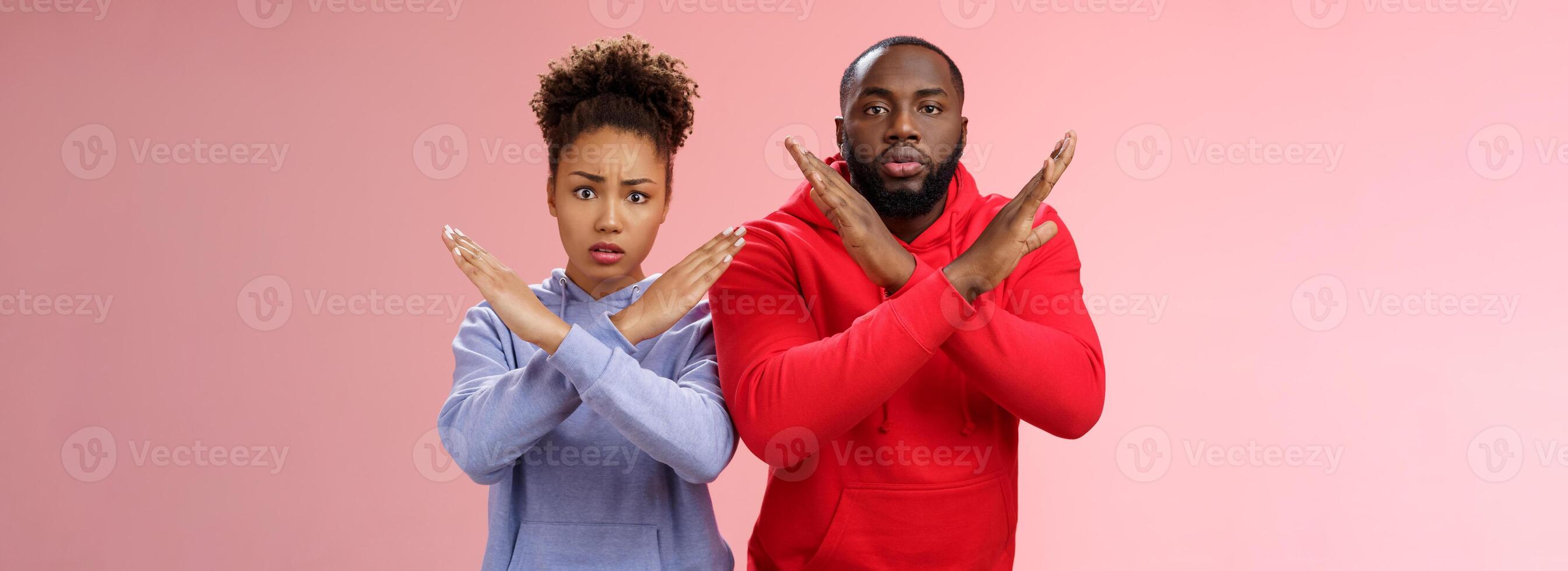 Nervous displeased two african-american man woman asking friend tell they absent not here show cross signs frowning disturbed worried begging not tell quit, stop standing pink background photo