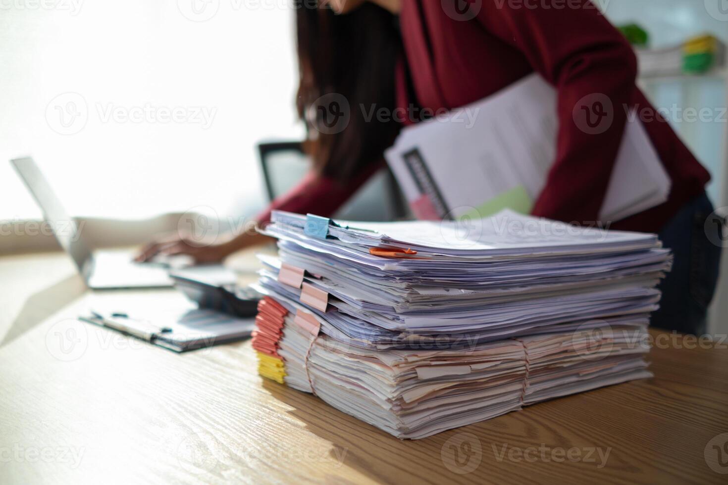 A young secretary receives a pile of documents to find important information for the company manager to use in a meeting. The concept of finding important documents from piles of overlapping documents photo