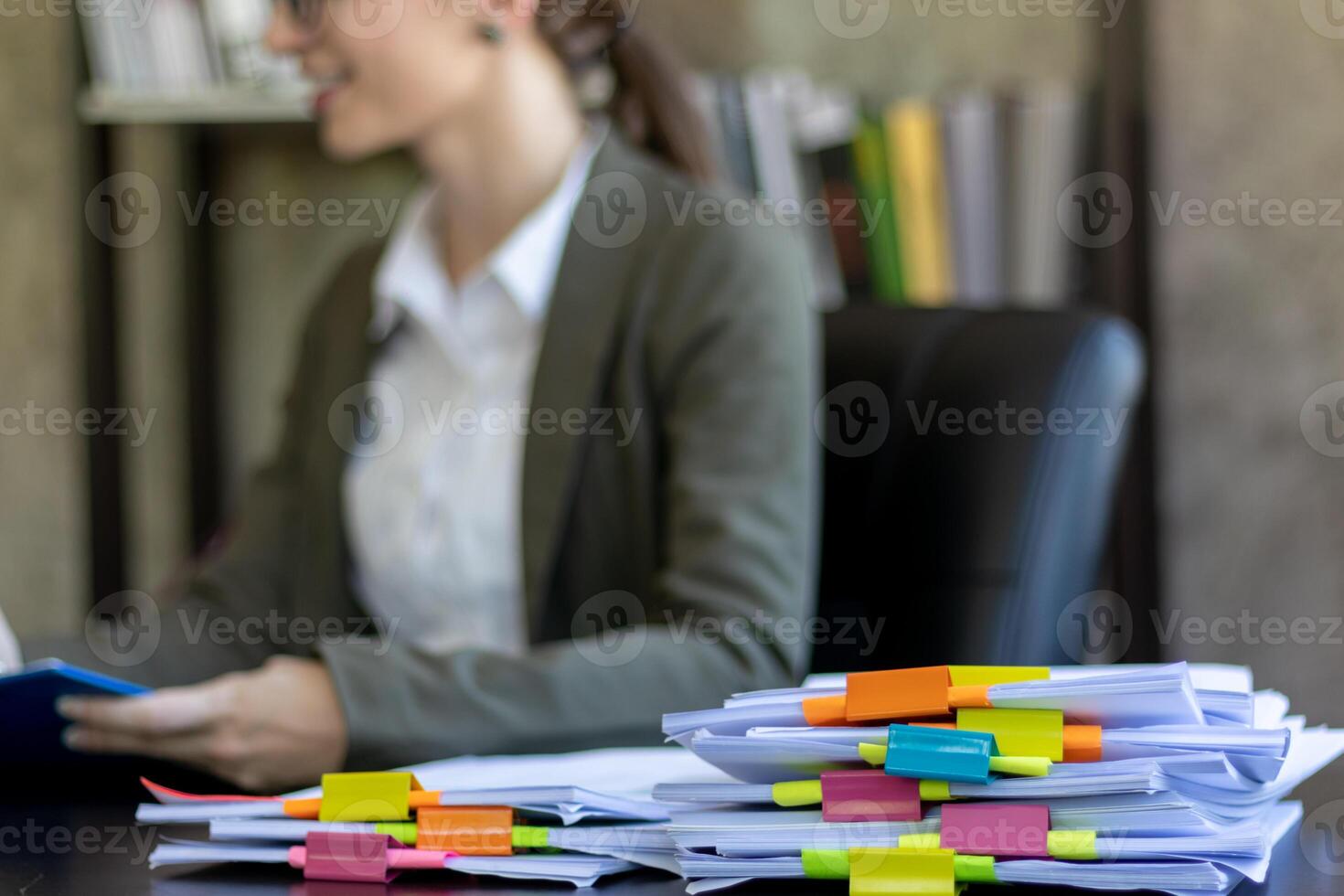 A young secretary receives a pile of documents to find important information for the company manager to use in a meeting. The concept of finding important documents from piles of overlapping documents photo