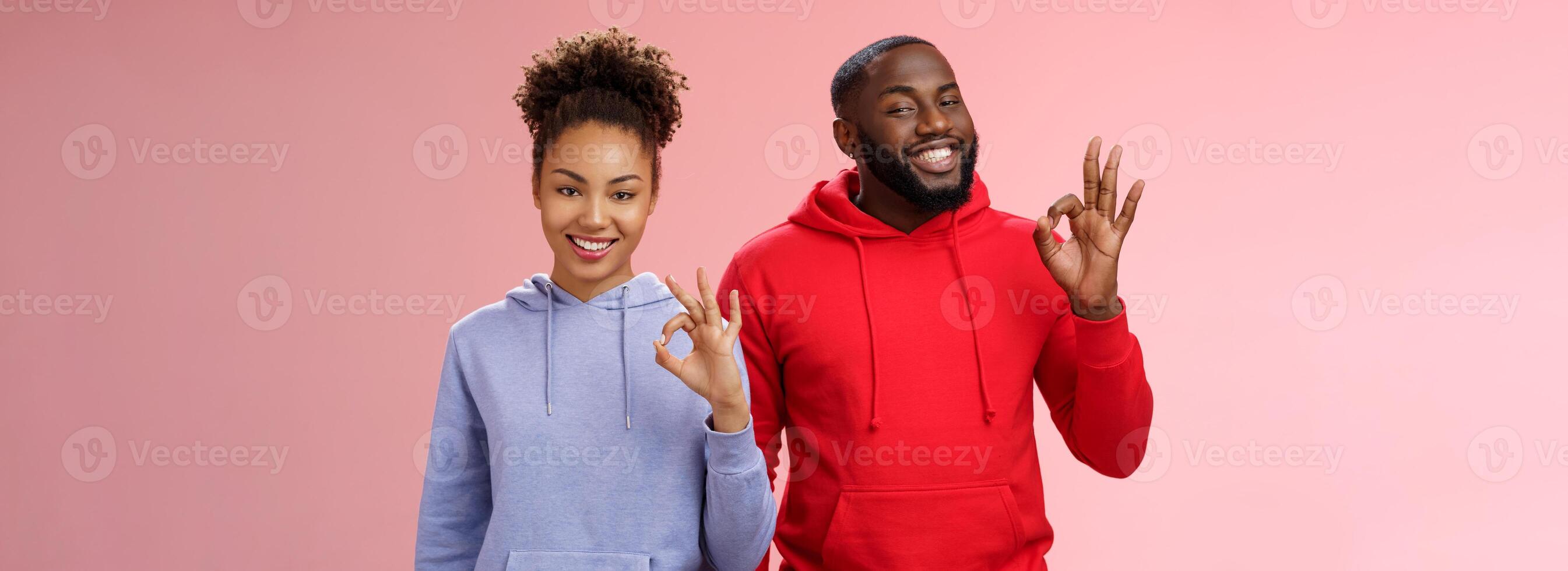 Two african-american skilful coworkers professionals assured friend everything perfect smiling broadly delighted nodding agree approval gesture show okay ok not bad choice sign, pink background photo