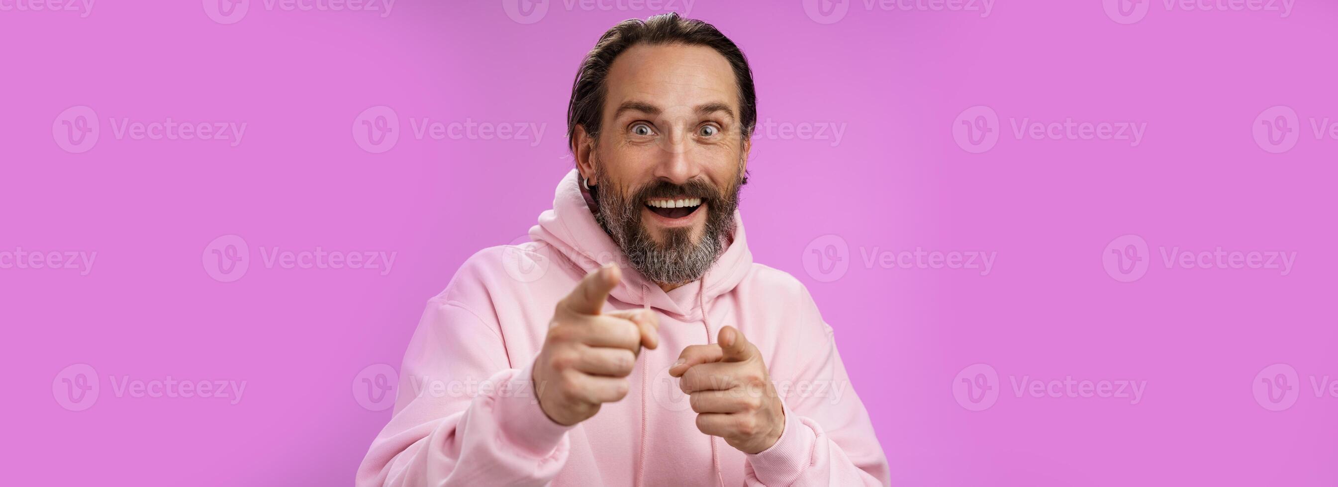 Thrilled energized charismatic happy lucky adult handsome bearded man pointing camera smiling widen eyes gazing impressed see famous person express amazement joy, purple background photo