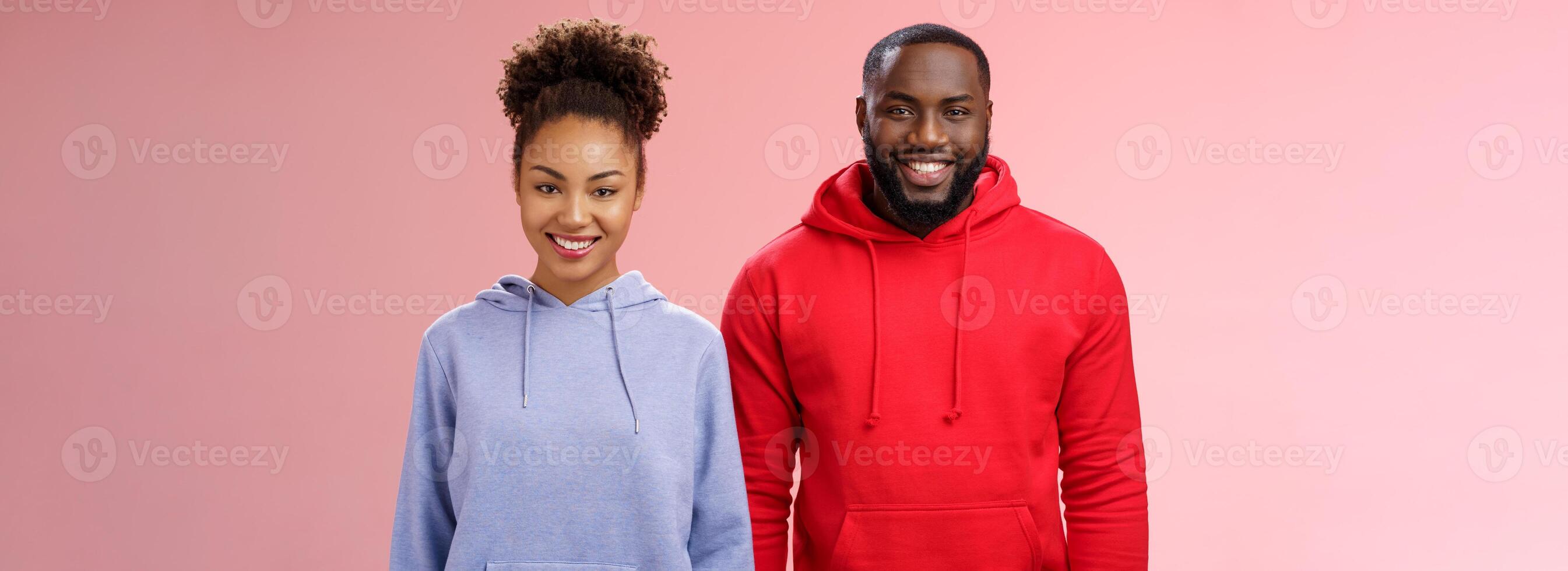 Friendly two african american man woman standing together smiling broadly coworkers present collective project receive good feedback grinning delighted like working pair, standing pink background photo