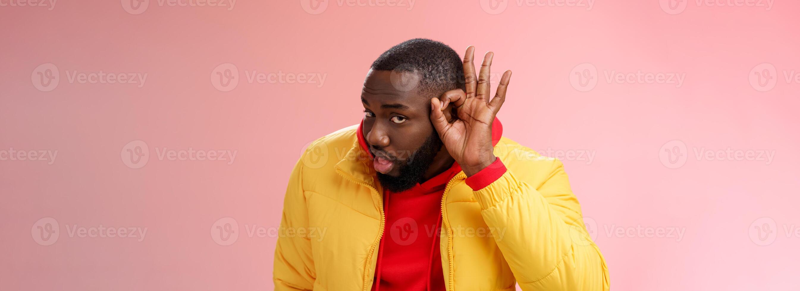 Curious funny charismatic black bearded guy bending forward hold hands ear eavesdropping wanna overhear girlfriend conversation behind door standing curious gossiping pink background photo