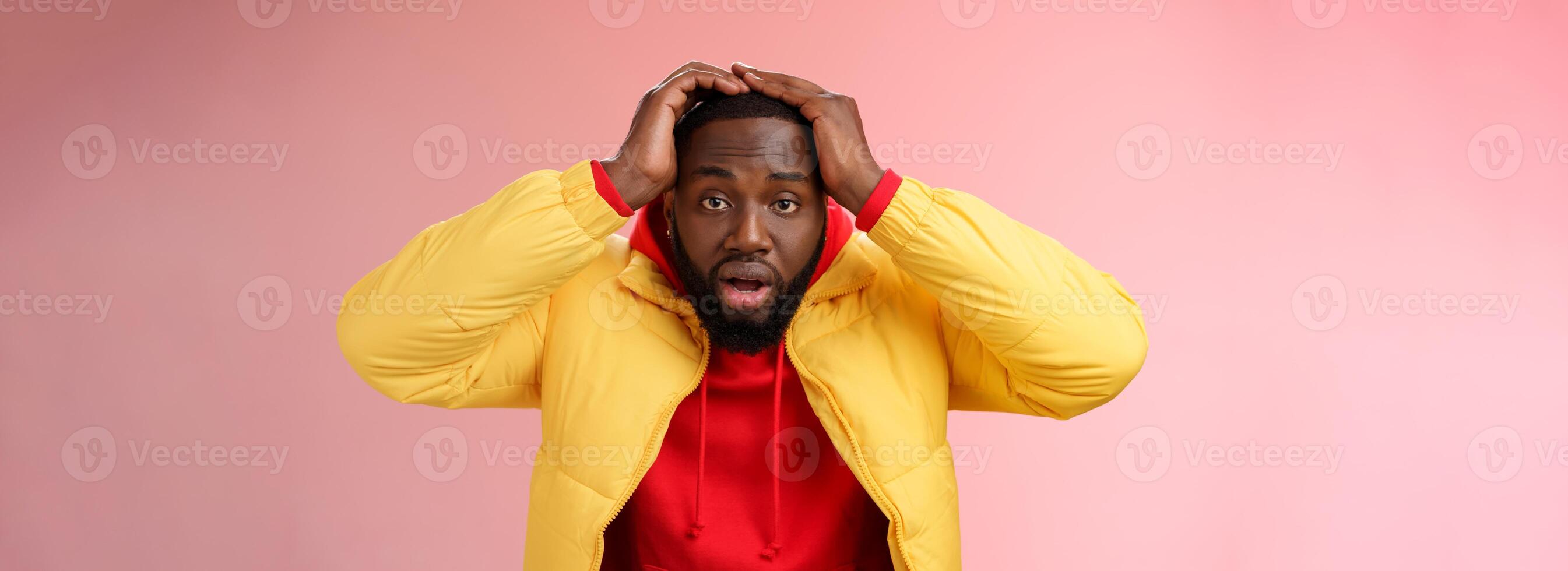 Shocked stupefied young african-american bearded man grab head drop jaw gasping confused frustrated looking upset troubled have problems standing stunned concerned pink background photo