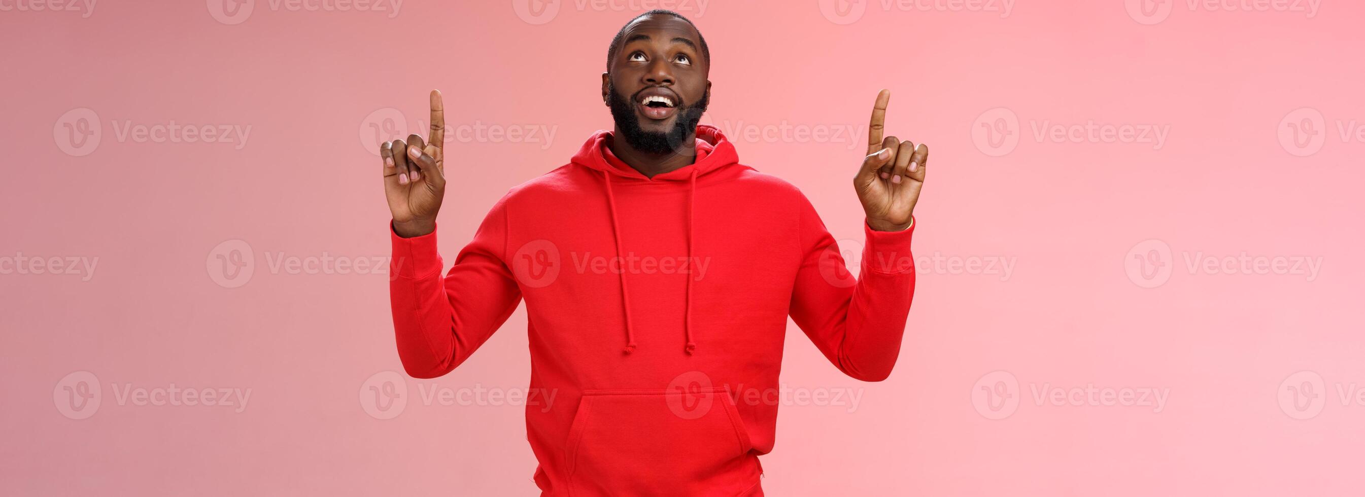 Fascinated attractive black bearded boyfriend gazing shooting star raise head impressed smiling amused pointing up curiously looking upwards, standing pink background enjoy stargazing photo