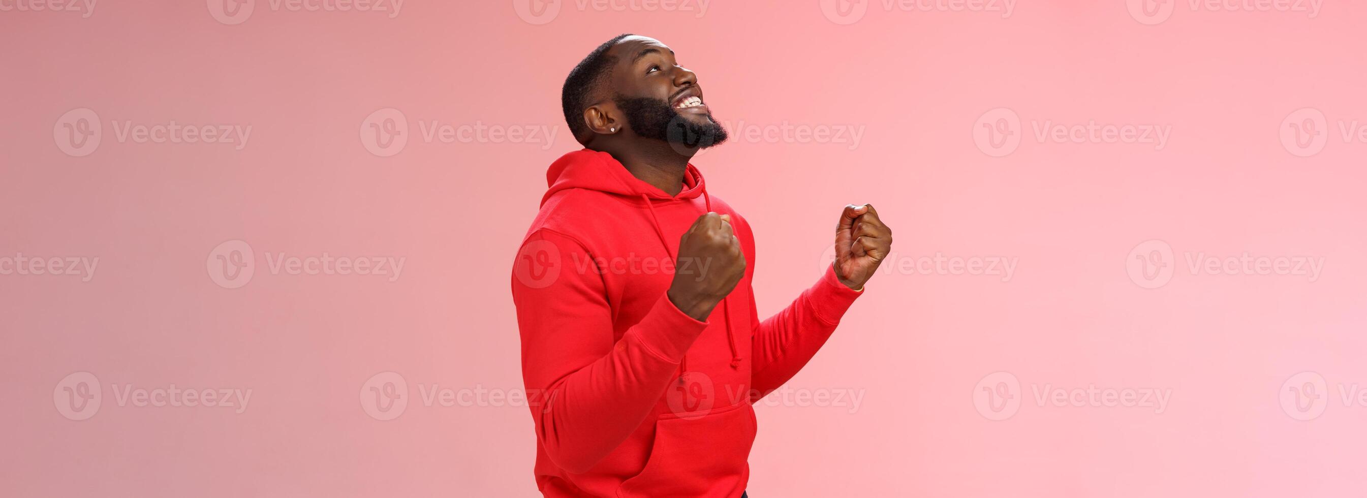 Extremely happy excited young african american man win lottery bet standing pleased jumping joyfully triumphing clench fists celebrating success look up smiling say yes finally accomplish goal photo