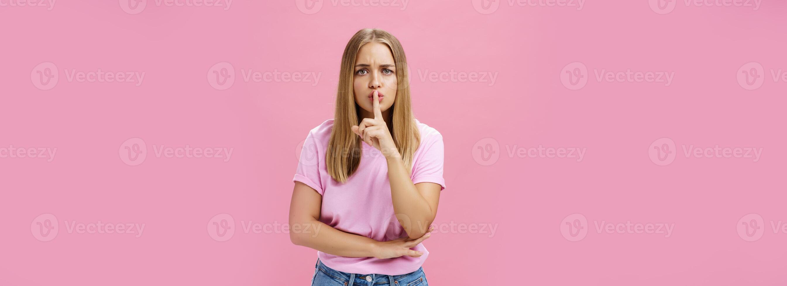 Shh keep voice down. Serious-looking concerned determined female nanny looking after kid asking not speak showing shush gesture with index finger over mouth, having secret concerned someone know it photo