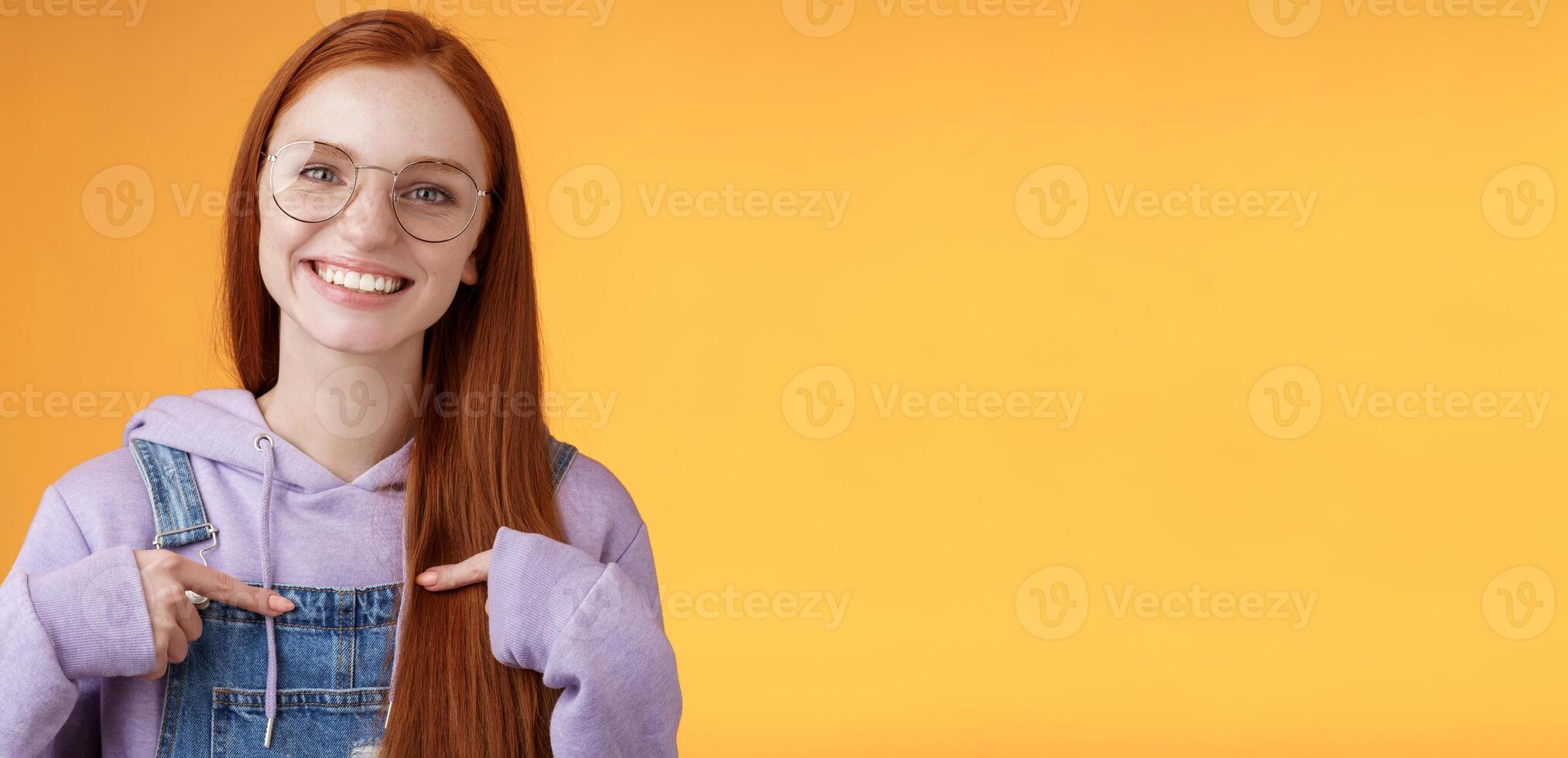 Happy lively friendly redhead european girl pointing herself suggesting help boasting telling own accomplishments smiling white teeth delighted volunteering, being picked, orange background photo