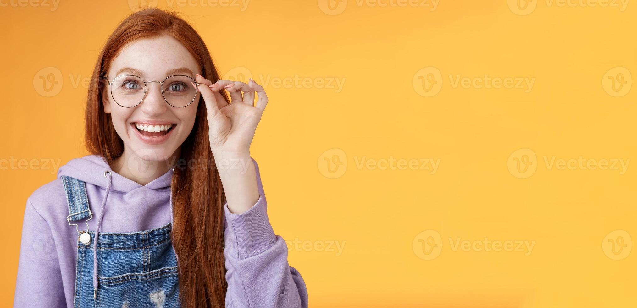 Happy enthusiastic young redhead girl amused find out excellent place celebrate b-day standing joyful excited touch glasses smiling broadly white teeth grinning rejoicing surprised, orange background photo
