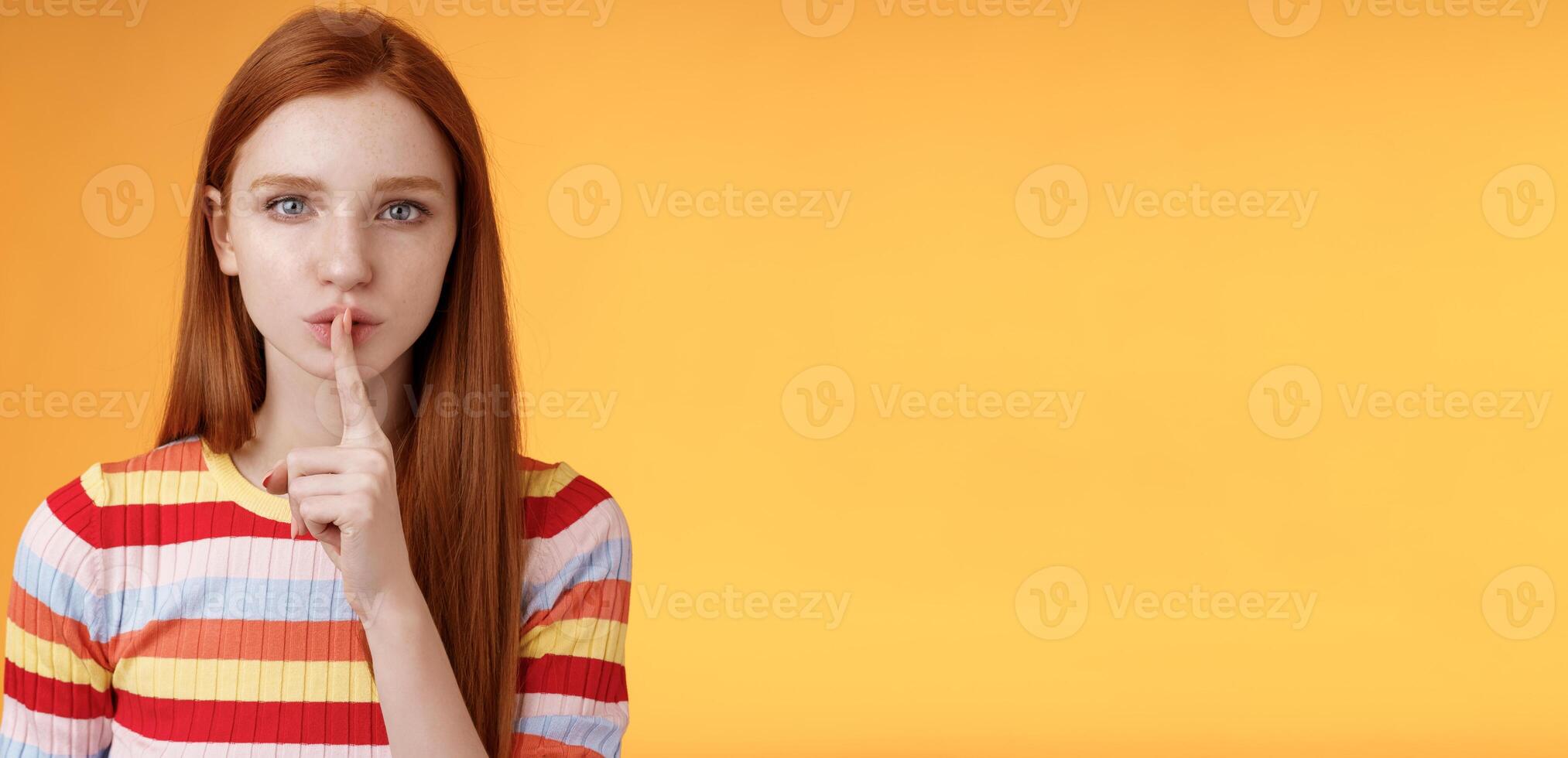 Girl hides lots secrets. Serious-looking redhead girlfriend blue eyes demand keep silent voice down show shhh shush gesture index finger pressed lips, prepare surprise, orange background photo