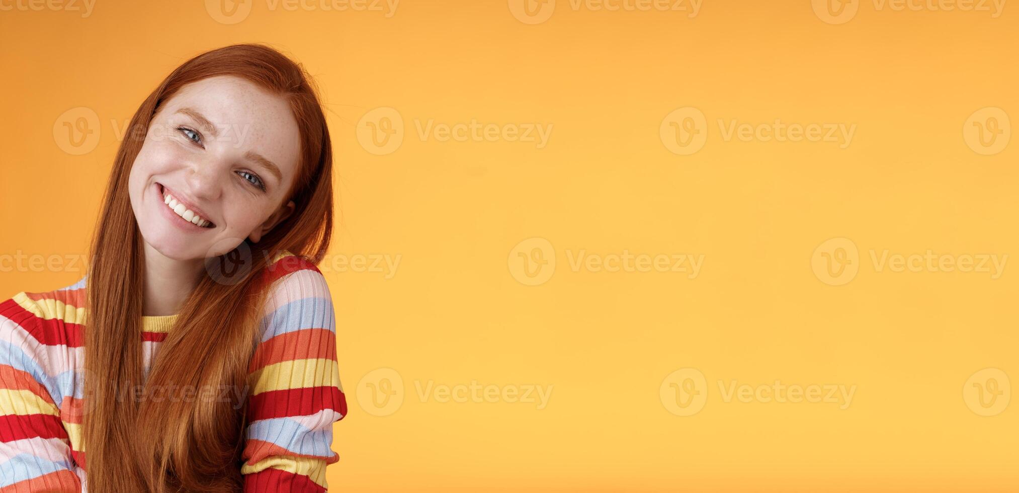 Tender lively cheerful smiling redhead european girl 20s tilting head leaning shoulder flirting grinning cute make lovely gazes camera coquettish talking boyfriend standing silly orange background photo