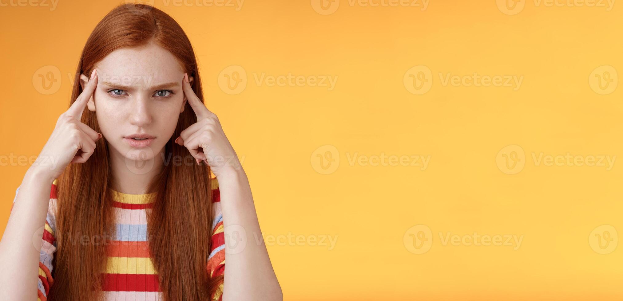 Puzzled serious-looking stressed-out young tired female student frowning look unhappy touching temples thinking trying focus, concentrate attention lecture memorizing hometask, orange background photo