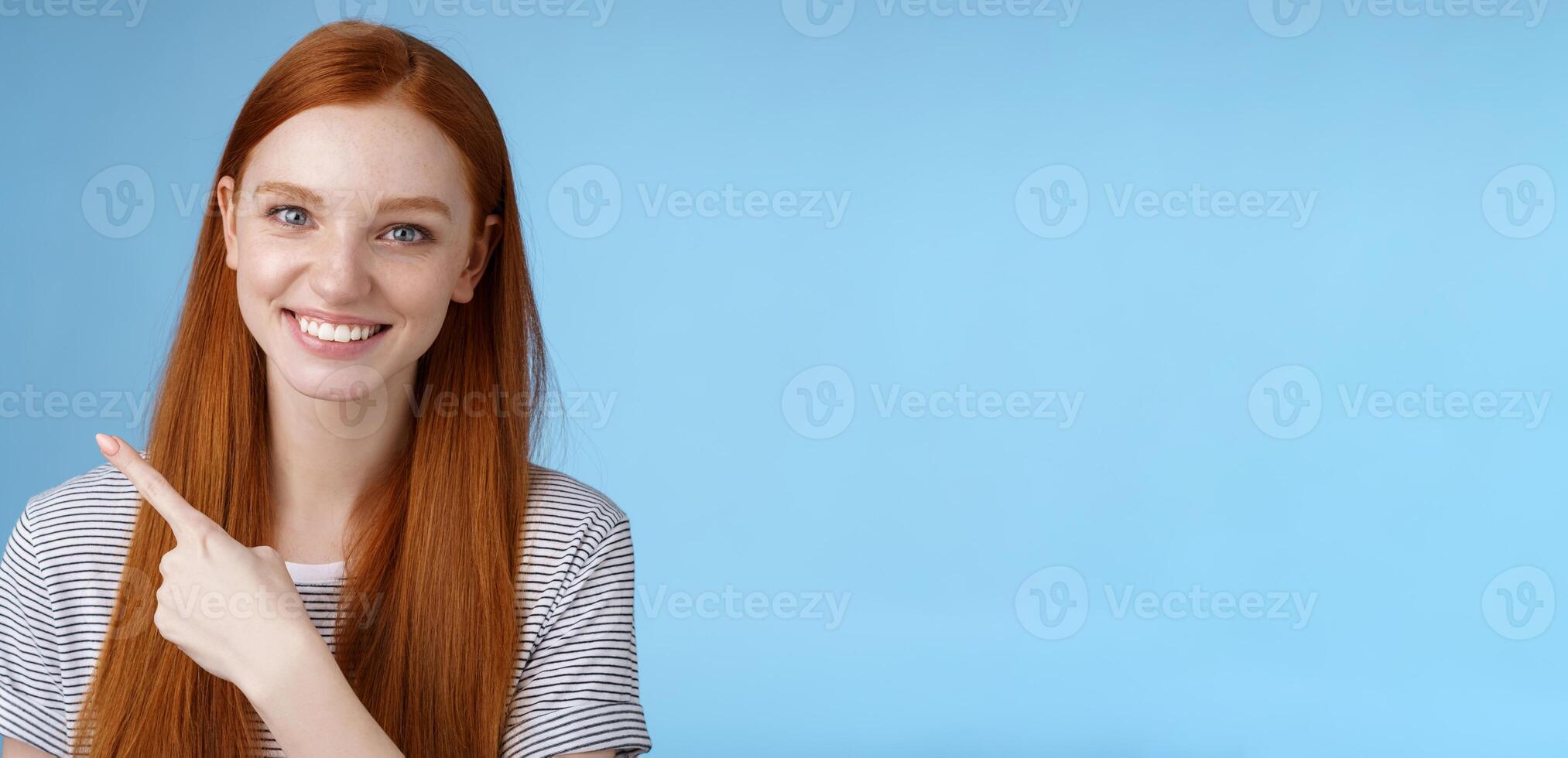 Close-up attractive gentle tender friendly-looking smiling redhead woman show place pointing upper left corner index finger grinning helpful giving choice help find store, standing blue background photo