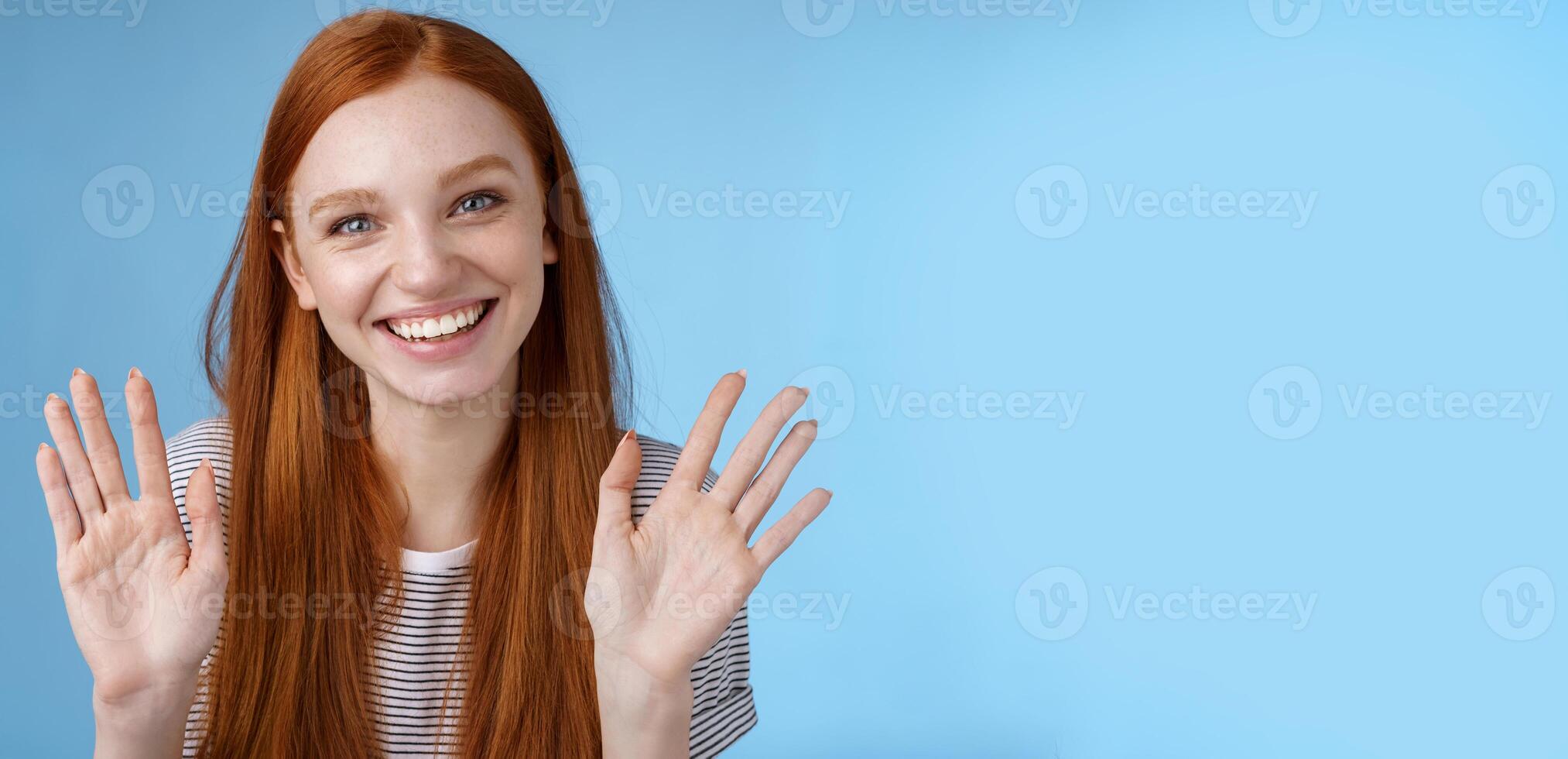 Charming redhead elder sister say goodbye sibling friends smiling cheerful waving raised palms show ten fingers grinning joyfully look carefree relaxed, talking casually blue background photo