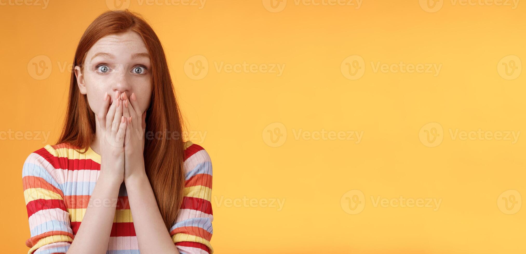 Shocked speechless impressed sensitive redhead european girl reacting stunning rumor gossiping find out secret gasping cover mouth palm stare camera astonished surprised, orange background photo