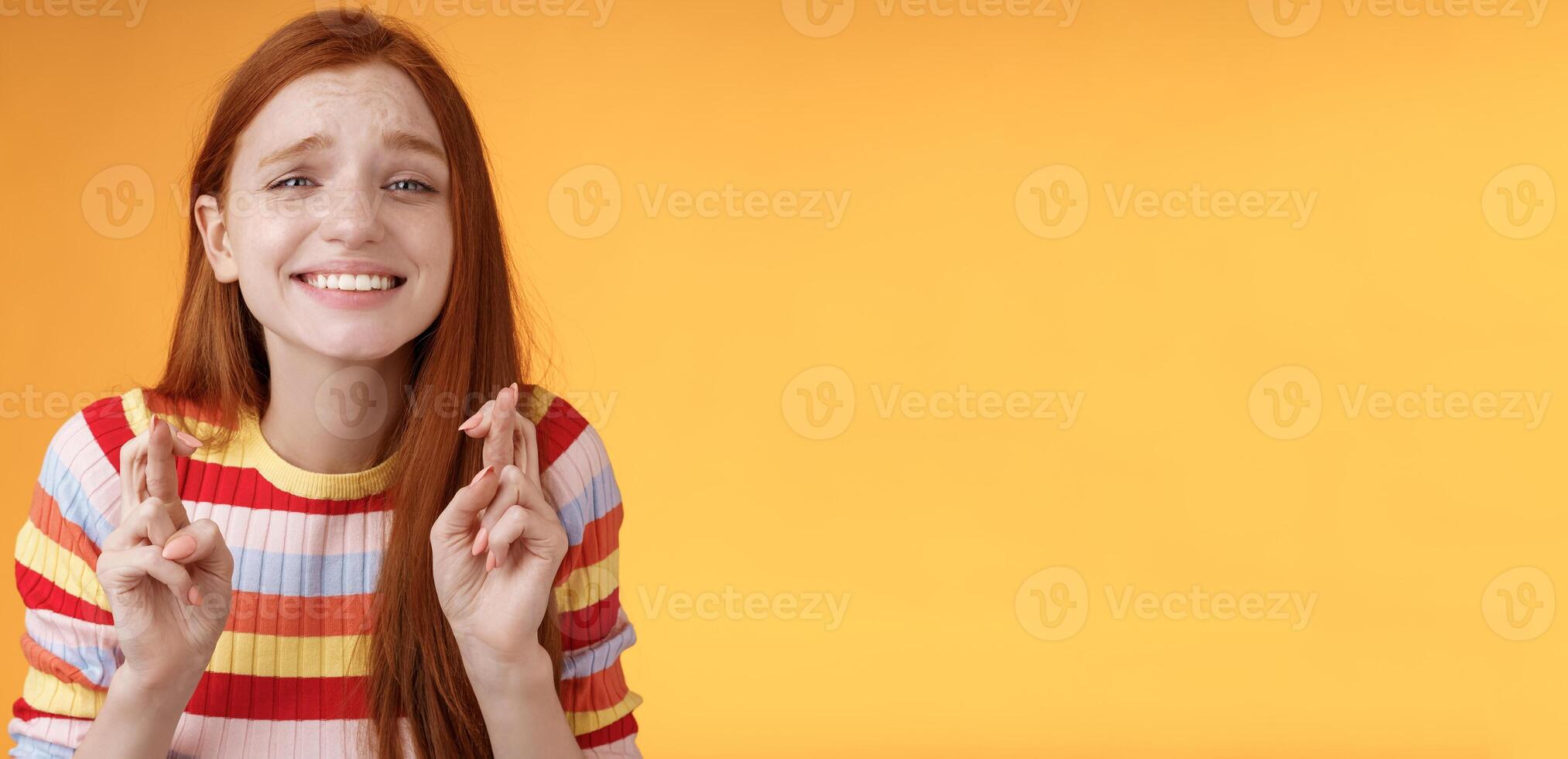 atractivo pelirrojo esperanzado niña anticipando bueno Noticias emoción emoción cruzar dedos bueno suerte sonriente en general Orando deseo ven cierto bueno resultados recibir premio, en pie naranja antecedentes deseo foto