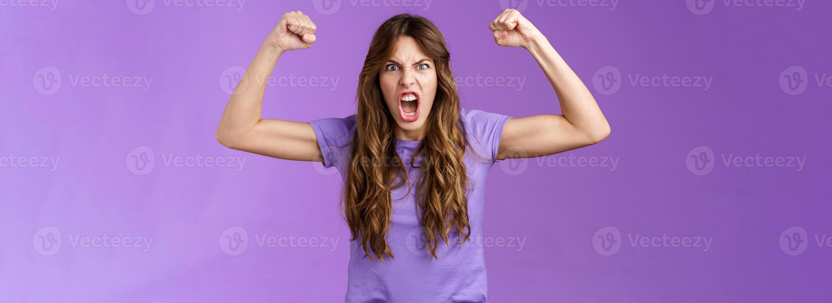 gracioso pelo rizado niña levantamiento manos puño bomba espectáculo músculos Gritando atrevido frio gritos alentado motivado ganar haciendo muecas fuerte poderoso mujer celebrando victoria sensación me gusta campeón foto