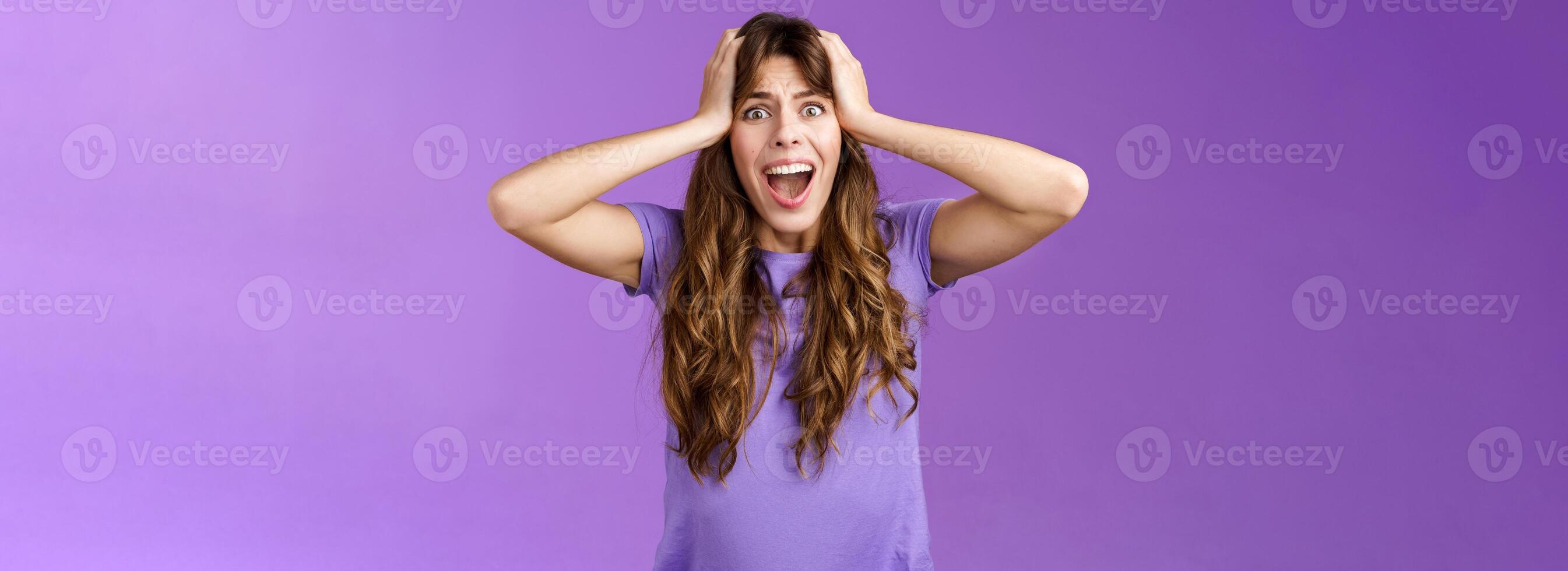 Shocked upset disappointed curly girl shouting sorrow face troublesome shocking situation grab head scream panic outraged pissed and angry, standing distressed purple background photo