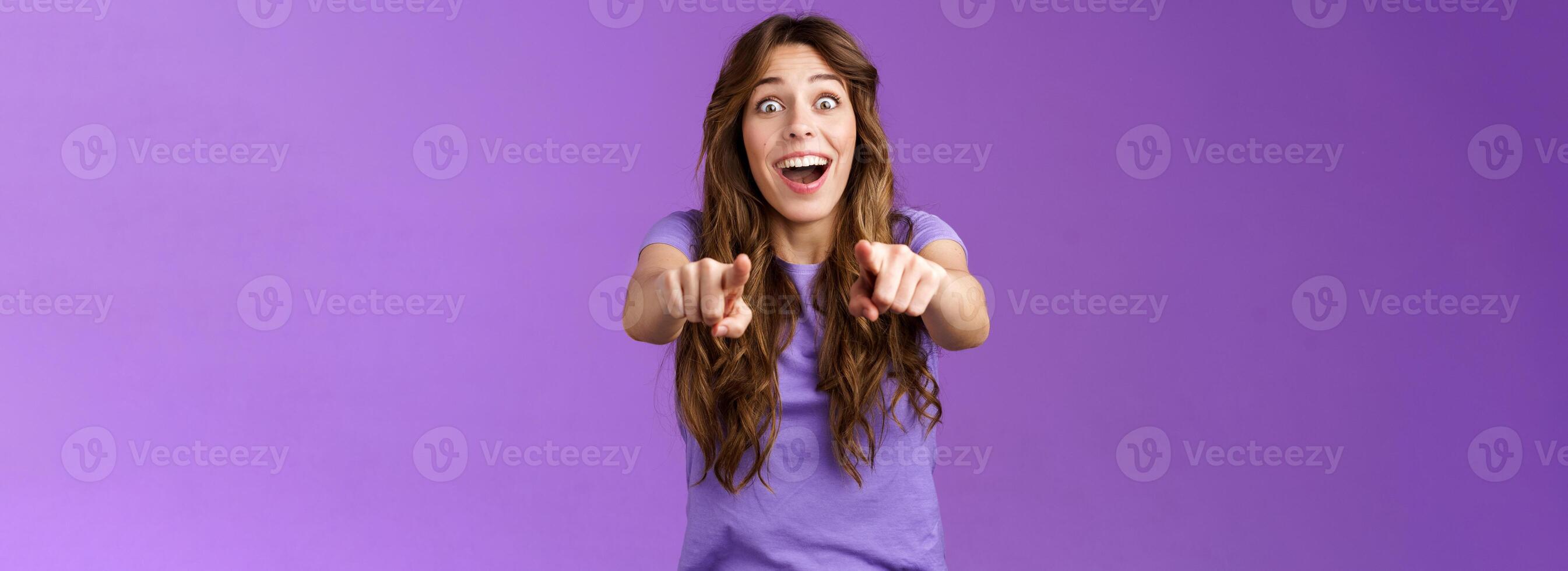 Omg its you. Surprised girl fan cheering joyfully gazing camera popping eyes pointing fingers forward astonished express admiration see superstar wanna receive autograph stand purple background photo