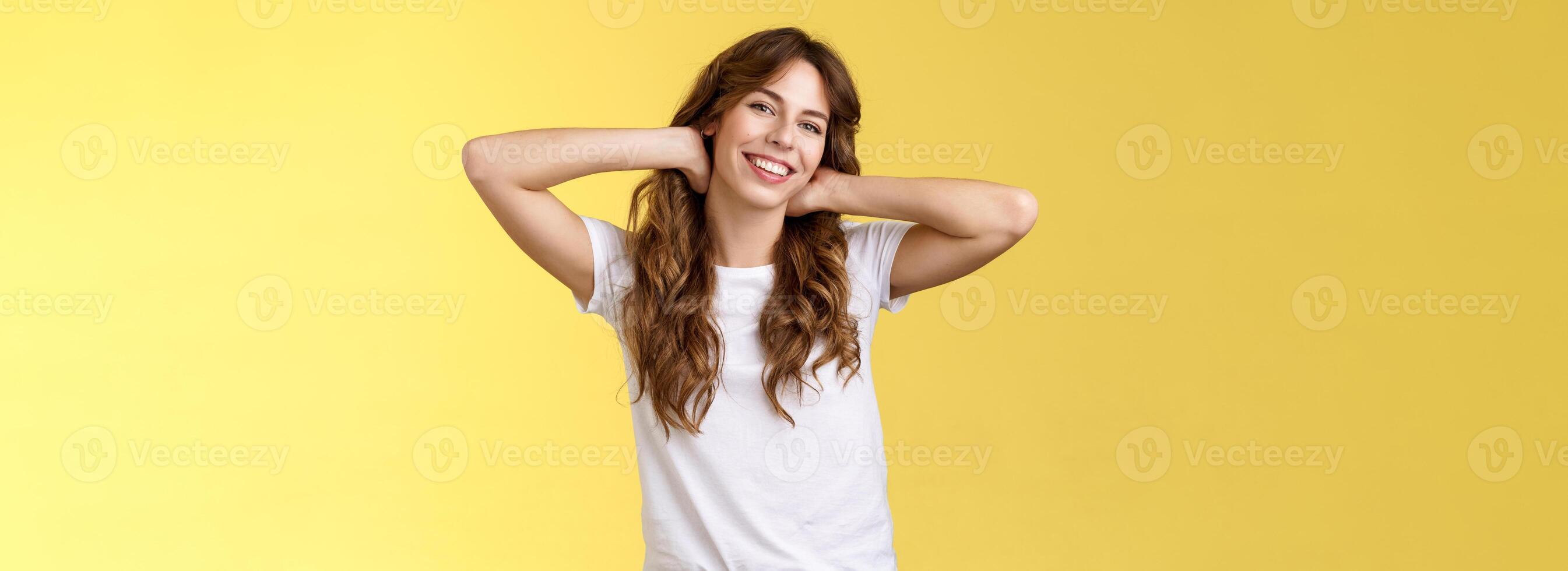 Carefree casual urban girl having summer holiday enjoy sunny perfect warm days wear white t-shirt jeans hold hands neck lazy stretch smiling broadly relaxing resting vacation stand yellow background photo