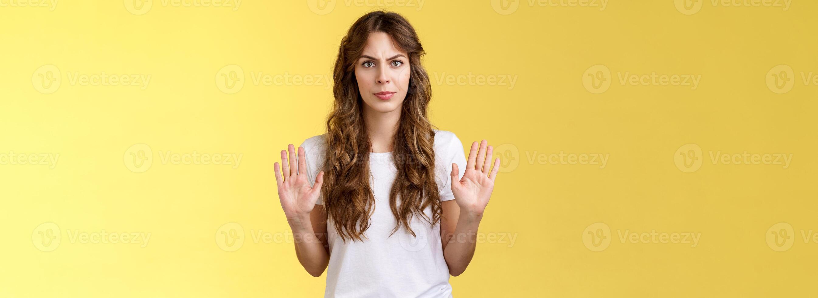 No thats enough. Serious-looking confident woman restrain man demand stay away give refusal look intense prohibit rejecting suspicious unpleasant offer stand yellow background photo