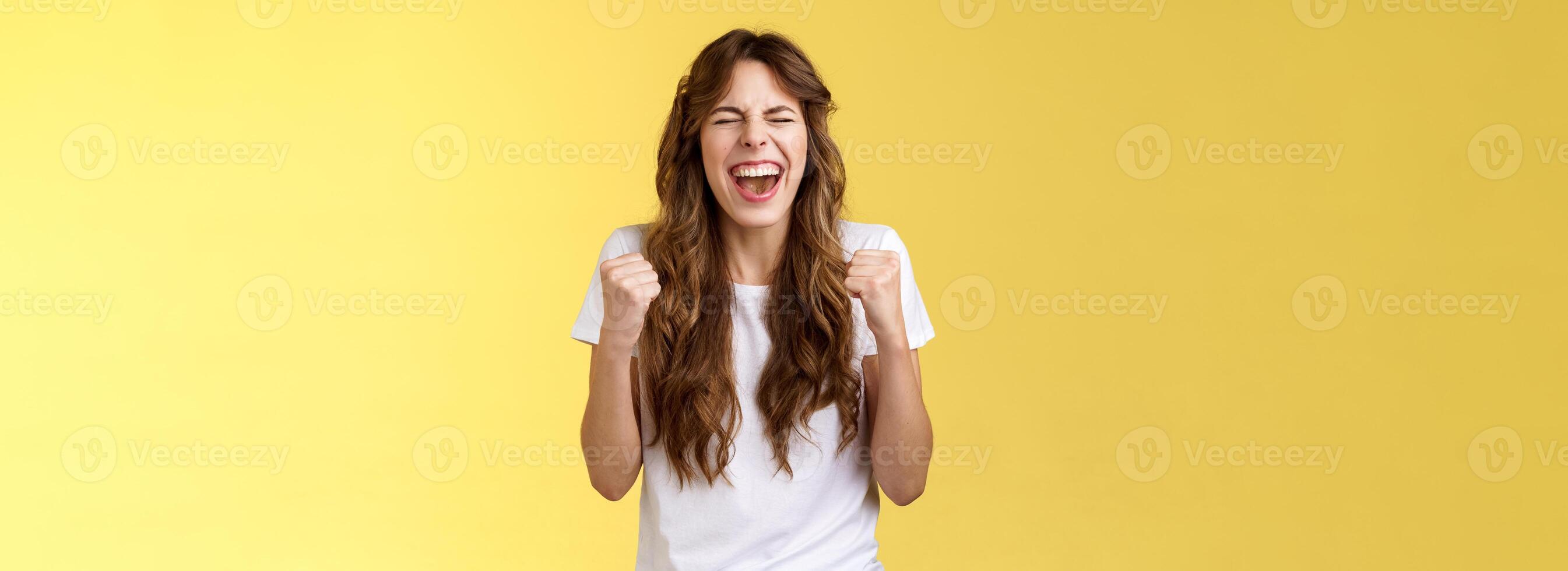 emocionado contento triunfando alegre caucásico niña cerca ojos puño bomba celebración felicidad gesto Gritando Si éxito alcanzar objetivo logro bailando victoria victorioso sensación aliviado amarillo antecedentes foto