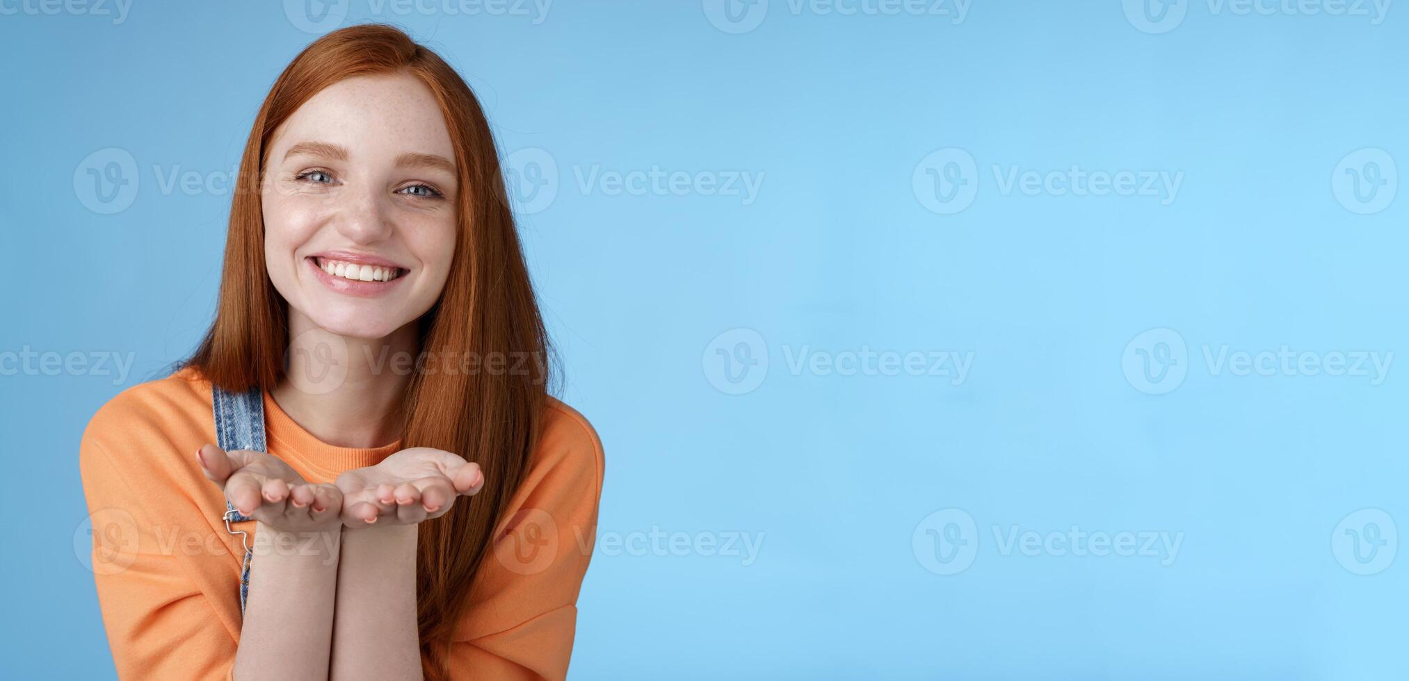 linda oferta tipo joven jengibre niña dando todas amor tú, sostener alguna cosa palmas demostración cámara sonriente Encantado introducir presente sonriendo romántico gesto enviar aire besos, azul antecedentes foto