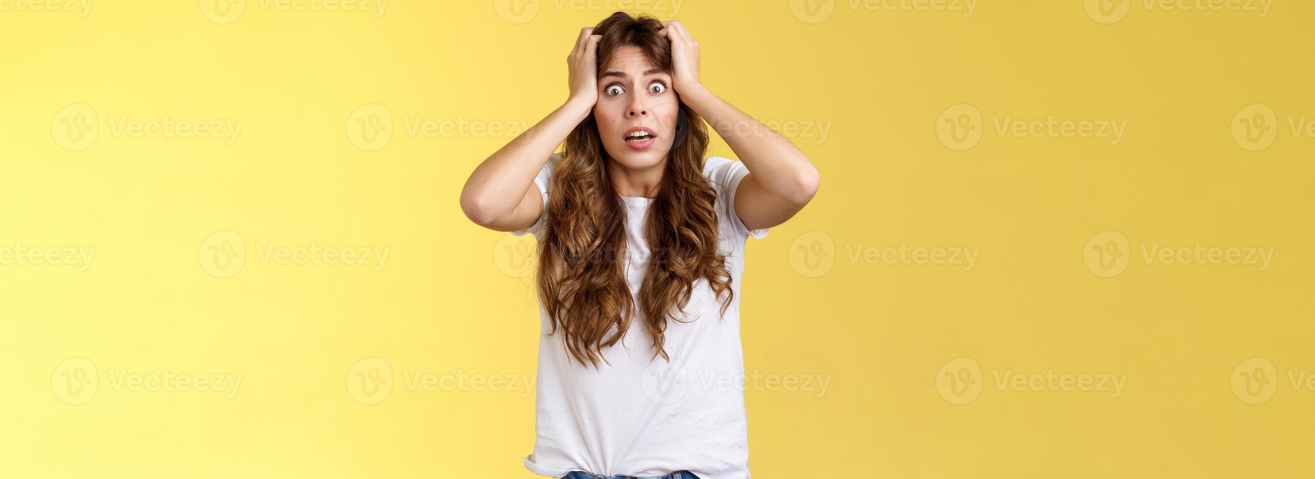 Troubled concerned anxious panicking woman female employee lose control grab head nervously stare camera frustrated scared gasping hopeless puzzled standing yellow background photo