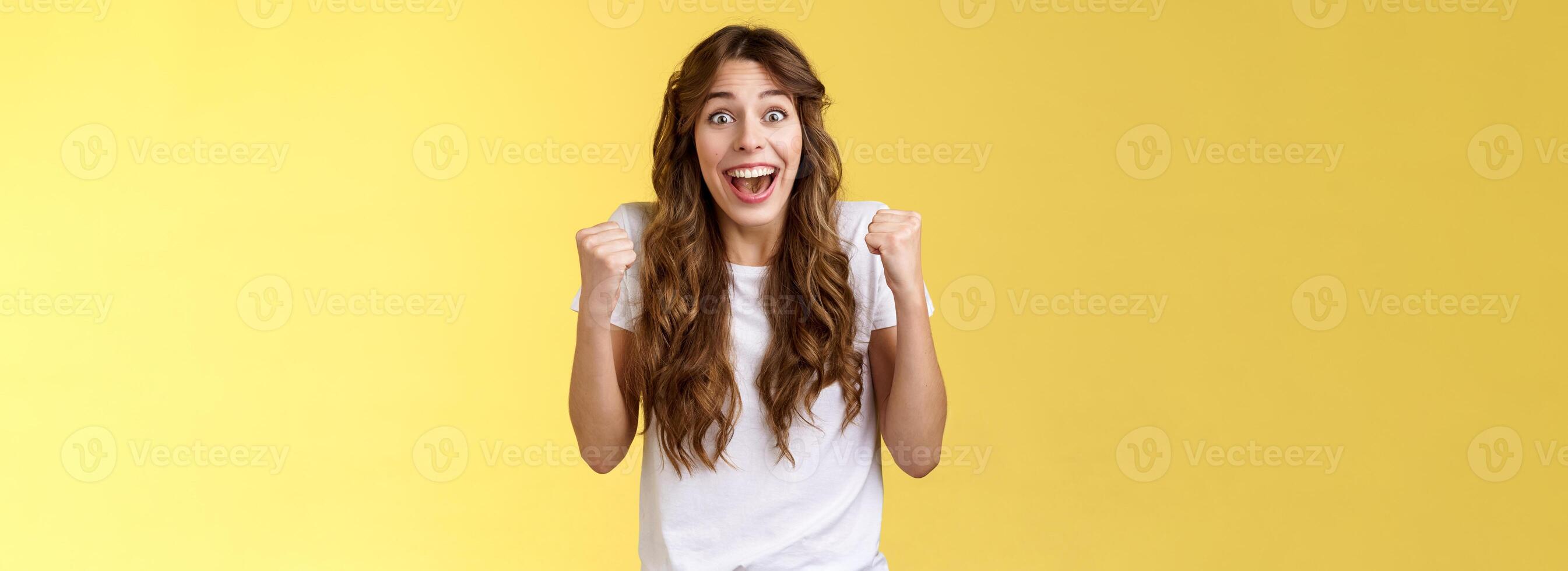 Cheerful supportive happy female fun fist pump relieved triumphing cheering rooting for favorite team winning smiling broadly hopefully look camera celebrating victory yellow background photo