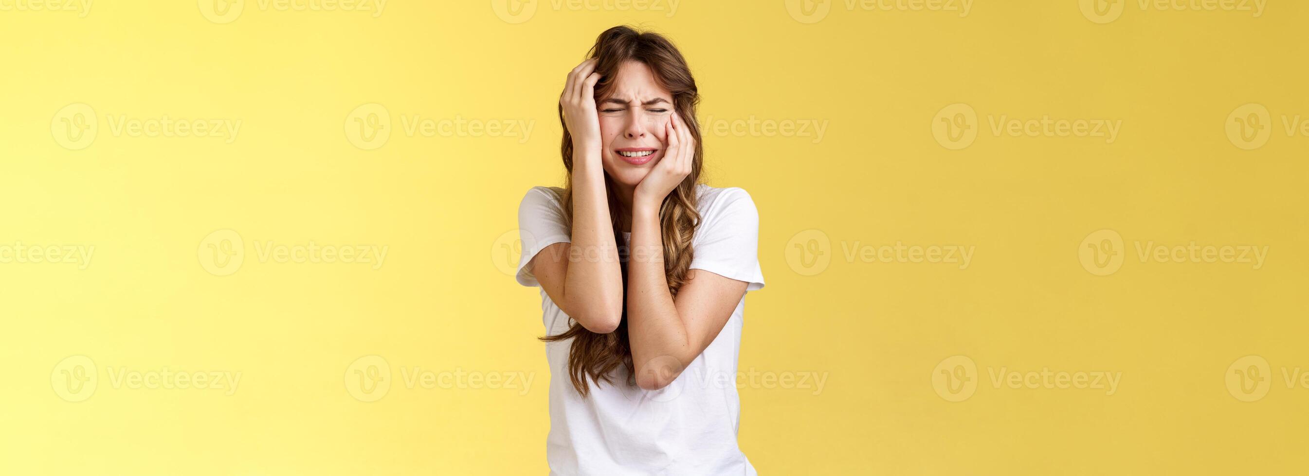 Offended silly timid insecure girl crying feel scared insulted close eyes whining grab head being victim sorry herself after huge quarrel sobbing stand yellow background upset distressed photo