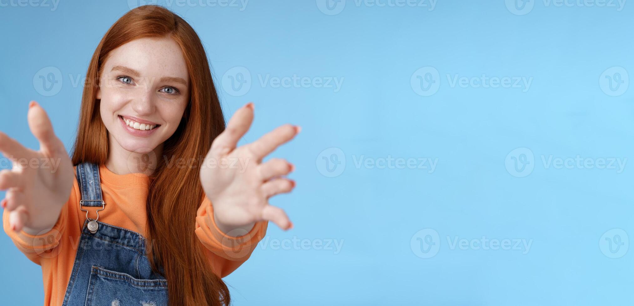 Come into arms. Charming sincere happy kind redhead girl baby sitting stretch hands camera wanna hold catch smiling friendly asking pass object, standing blue background reach friend give cuddles photo