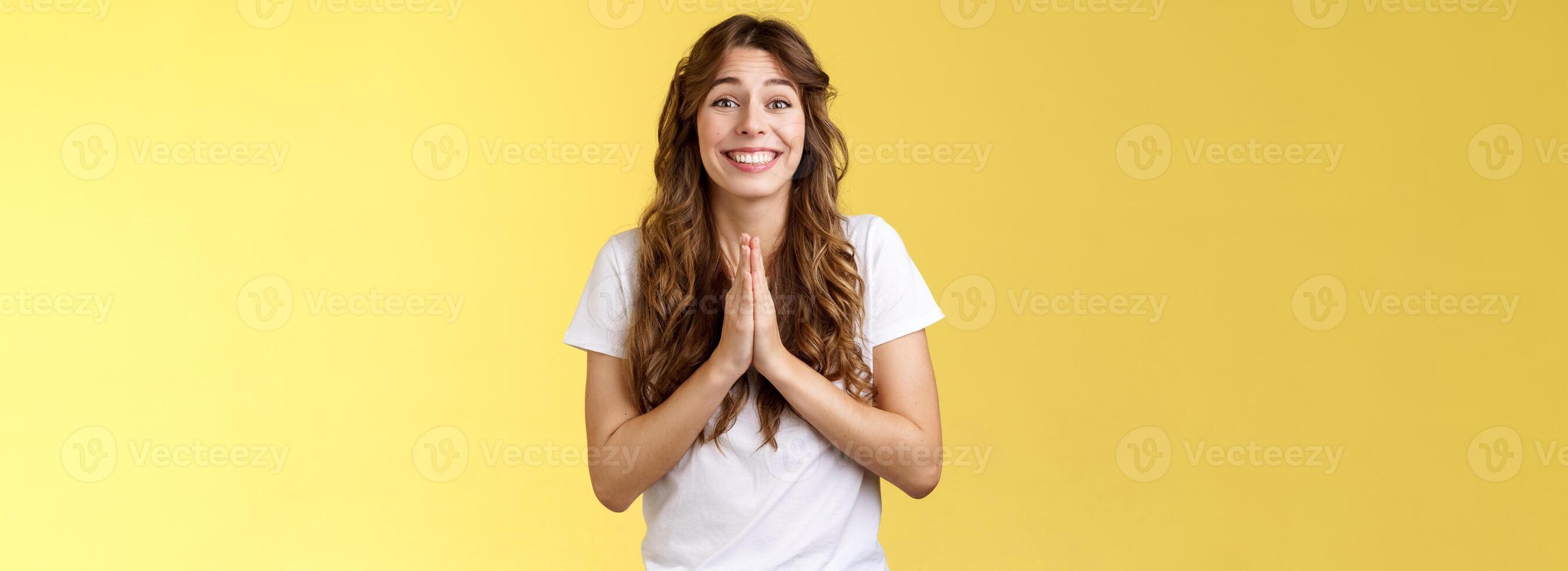 Please one small favor. Cute silly charming young girlfriend asking lend money press palms together praying supplication gesture implore you help hopefully smiling begging yellow background photo