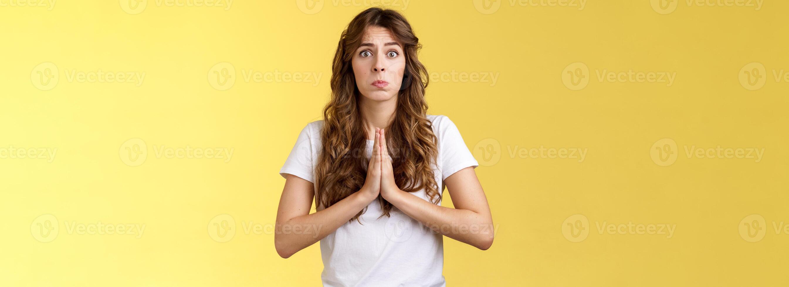 Pretty please beg you help me. Innocent cute lovely upset caucasian girl begging pleading your mercy pulling face hope for pity apologizing puppy eyes frowning need urgent advice yellow background photo