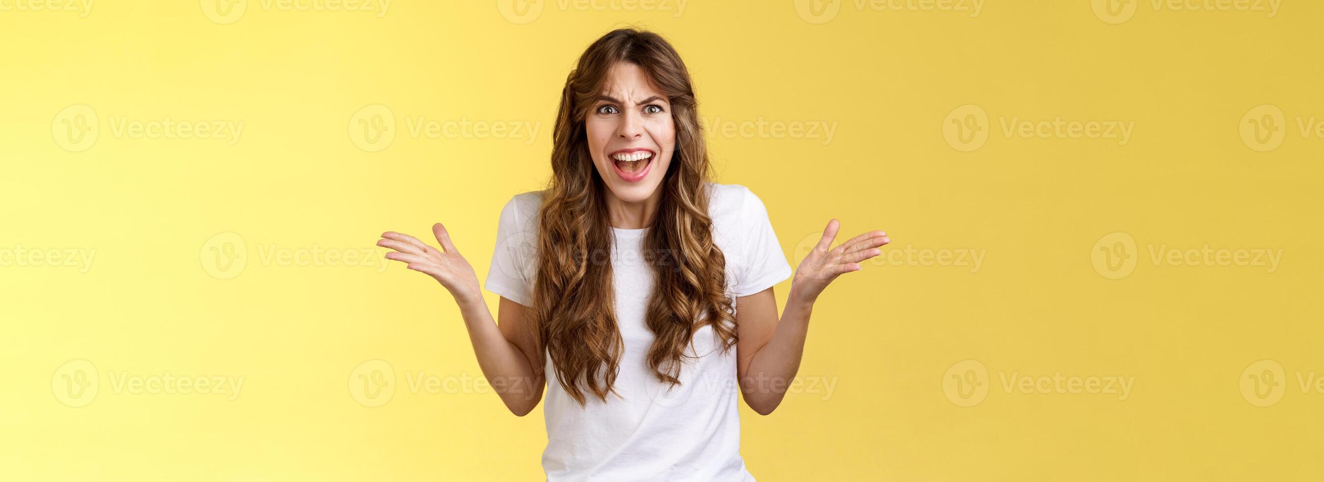 Disappointed angry furious woman shrugging hands sideways dismay frustration shouting complaining feel outraged pissed arguing scream intense rage stand yellow background quarrel photo