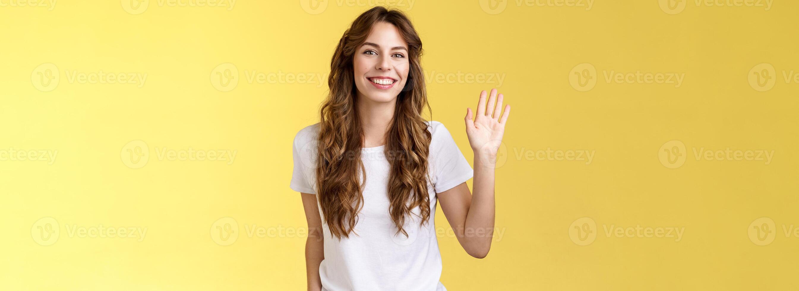 saliente cómodo relajado simpático casual europeo mujer Rizado Corte de pelo ondulación elevado palma decir Hola introducir sí misma volverse nuevo miembro sonriente en general saludo Hola gesto amarillo antecedentes foto