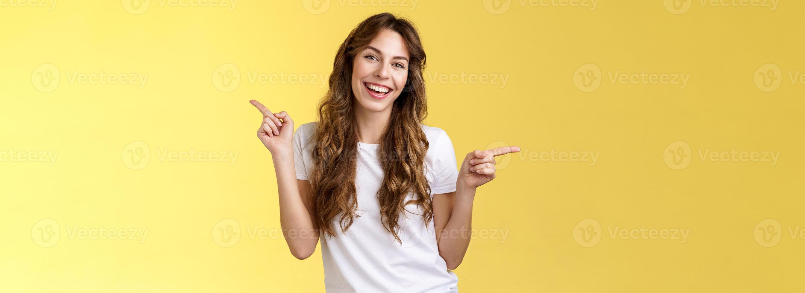 Girl have two suggestions pointing sideways. Cheerful charismatic curly-haired attractive woman pointing left right index fingers introduce promo products smiling broadly lively recommend ad photo